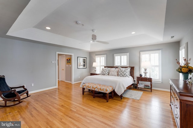 bedroom with baseboards, recessed lighting, a raised ceiling, and light wood-style floors