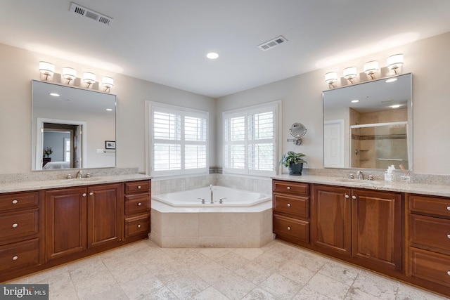full bathroom with two vanities, visible vents, a shower stall, and a sink