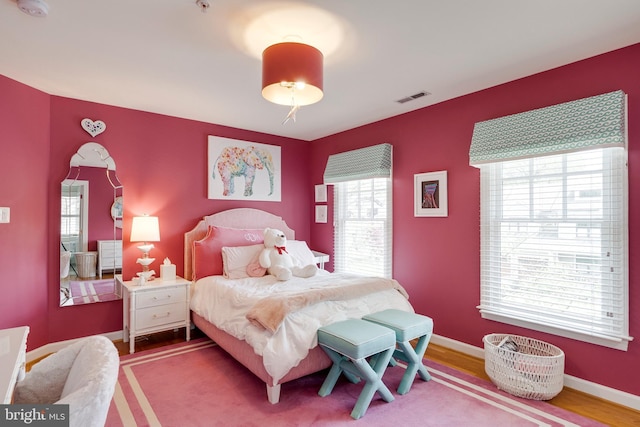bedroom with visible vents, baseboards, and wood finished floors