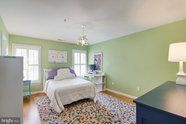 bedroom with baseboards, wood finished floors, and visible vents