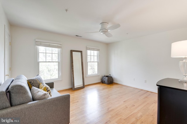 living area with a healthy amount of sunlight, baseboards, ceiling fan, and light wood-style floors