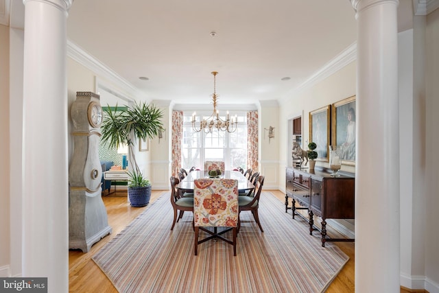 dining space with decorative columns, an inviting chandelier, and light wood-style floors
