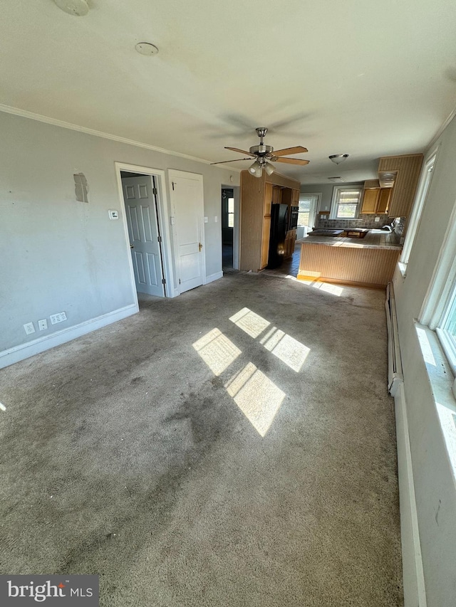 unfurnished living room with baseboards, baseboard heating, ornamental molding, and dark carpet