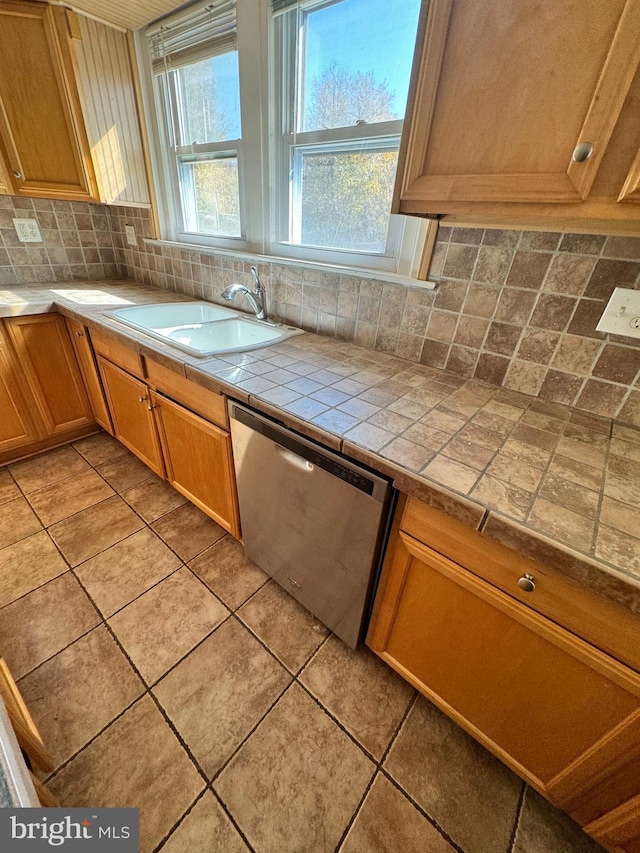 kitchen with a wealth of natural light, a sink, backsplash, light tile patterned flooring, and dishwasher