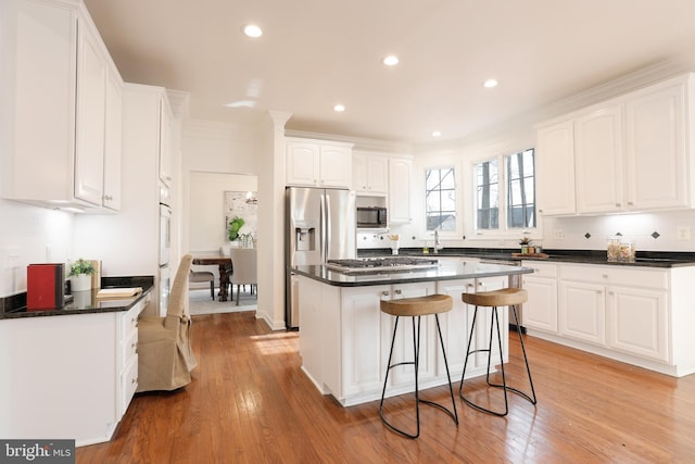 kitchen featuring stainless steel appliances, light wood finished floors, dark countertops, and white cabinetry