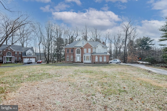 view of front of house with brick siding, a chimney, and a front yard