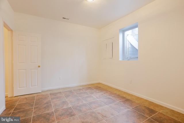 tiled spare room featuring baseboards and visible vents