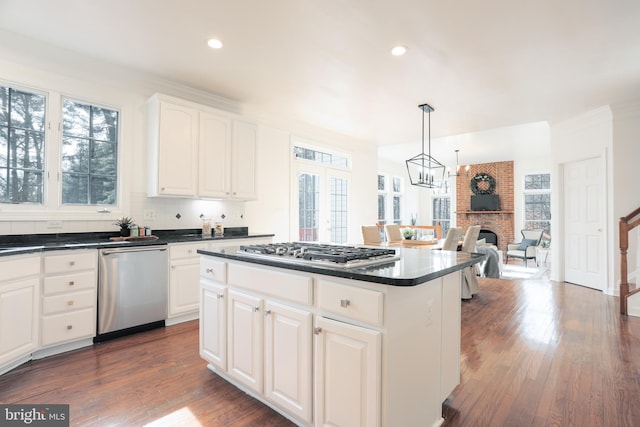 kitchen featuring stainless steel appliances, dark countertops, dark wood-style floors, and a center island