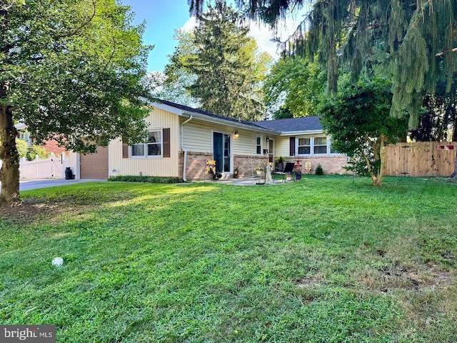 rear view of property featuring brick siding, fence, a lawn, crawl space, and driveway