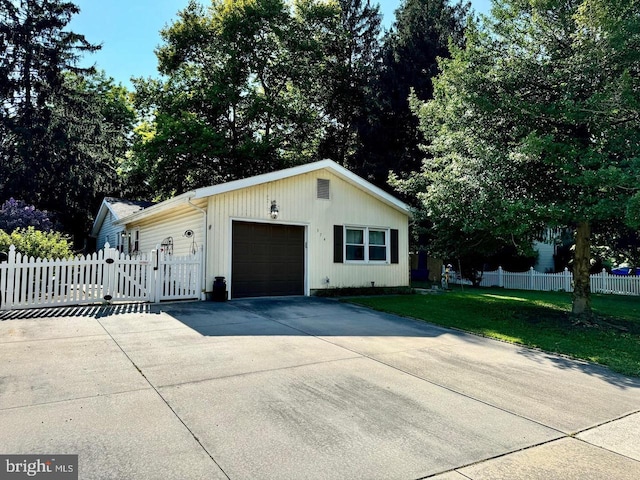 garage with a gate, concrete driveway, and fence