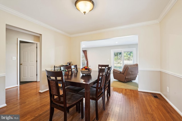 dining area featuring hardwood / wood-style floors, baseboards, visible vents, and ornamental molding