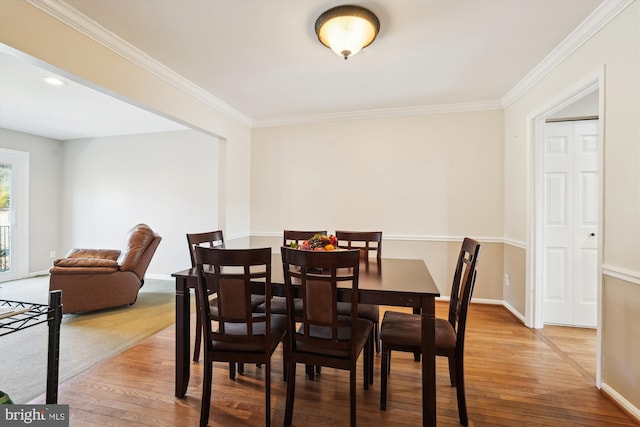 dining area with light wood-type flooring, baseboards, and ornamental molding