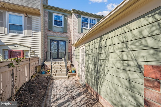 entrance to property featuring brick siding and fence