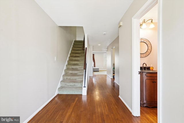 hallway with stairway, dark wood-style floors, and baseboards