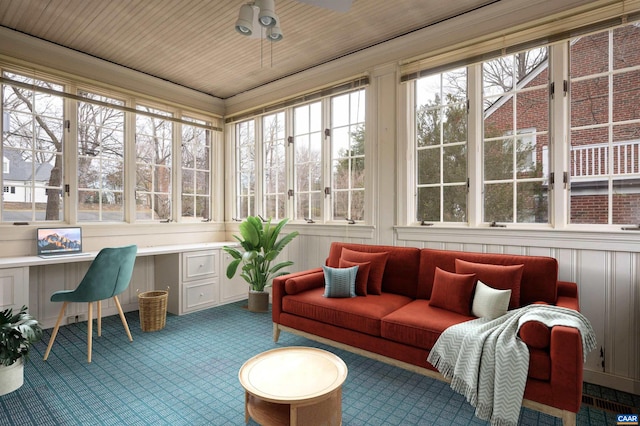 sunroom / solarium featuring a ceiling fan and built in desk