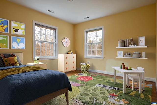 bedroom with wood finished floors, visible vents, and baseboards