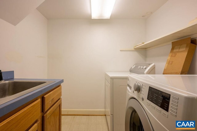 washroom with light floors, baseboards, cabinet space, a sink, and washer and clothes dryer