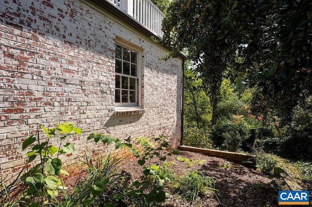 view of property exterior featuring brick siding and a balcony