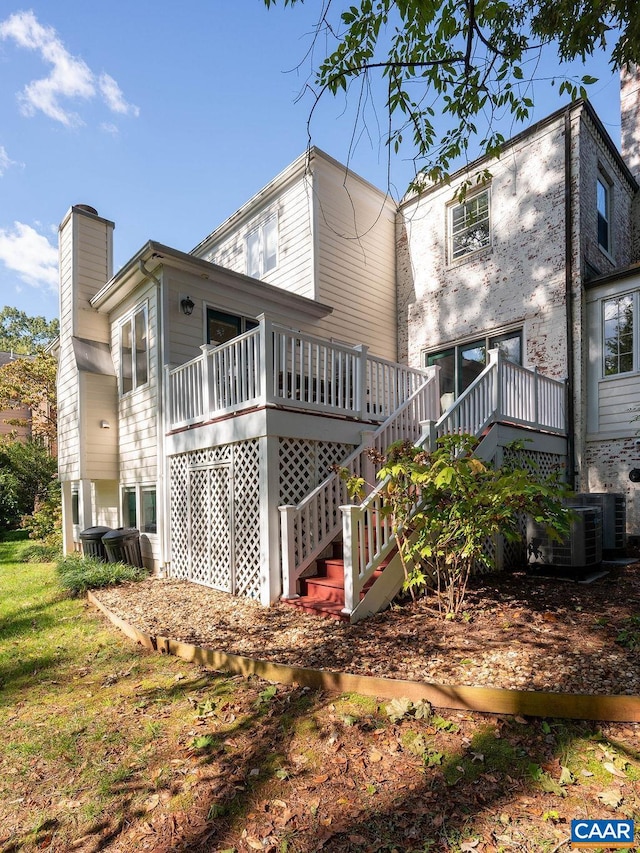 back of property featuring a wooden deck, a chimney, and stairs