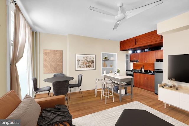 interior space with brown cabinetry, light wood-style flooring, freestanding refrigerator, ceiling fan, and stainless steel gas range oven