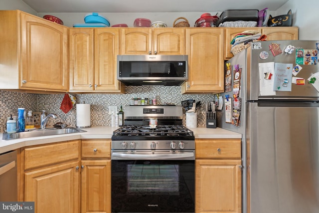 kitchen with backsplash, appliances with stainless steel finishes, light countertops, and a sink