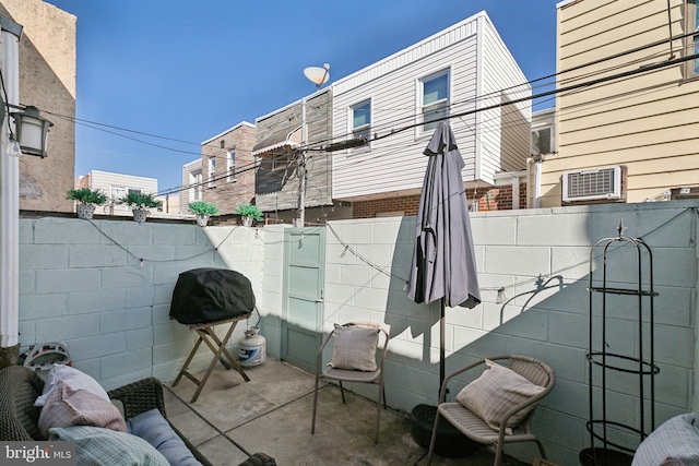 view of patio featuring area for grilling, a wall mounted air conditioner, and fence