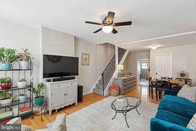 living room with light wood-type flooring, stairs, and ceiling fan