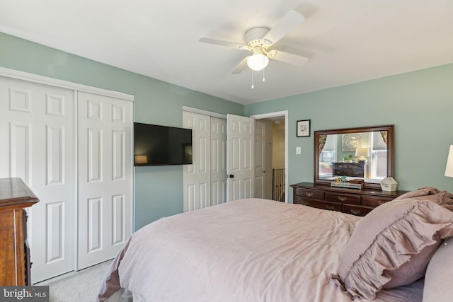 carpeted bedroom featuring multiple closets and a ceiling fan