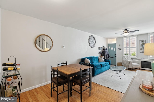 dining room featuring baseboards, light wood-style flooring, and a ceiling fan