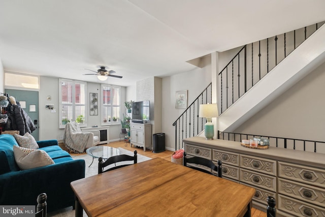 dining space featuring a ceiling fan, stairway, wood finished floors, and baseboards