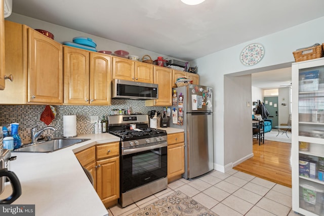 kitchen featuring light countertops, backsplash, appliances with stainless steel finishes, and a sink