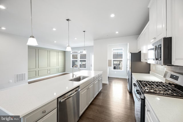 kitchen featuring dark wood-style floors, visible vents, a sink, appliances with stainless steel finishes, and tasteful backsplash