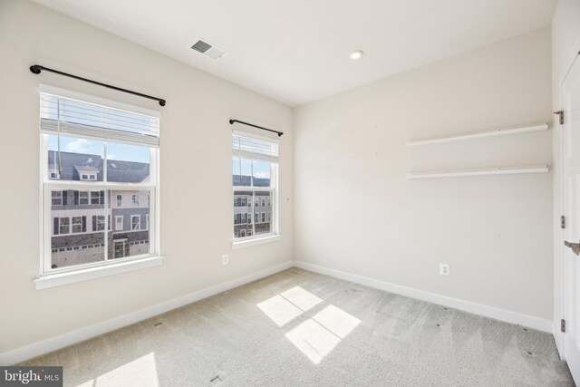 carpeted spare room with visible vents and baseboards