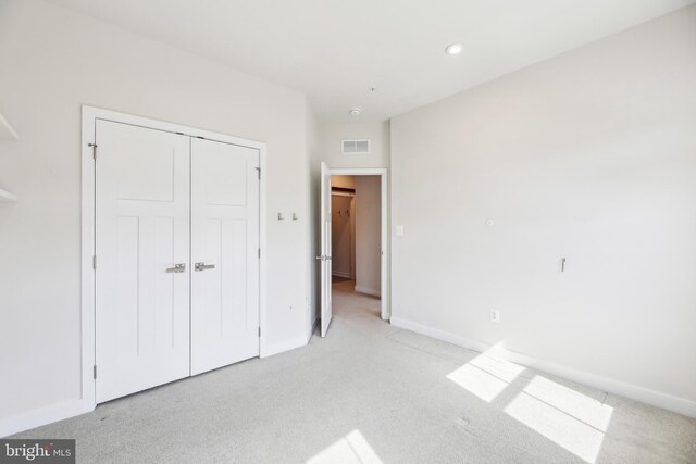 unfurnished bedroom with light colored carpet, baseboards, visible vents, and a closet