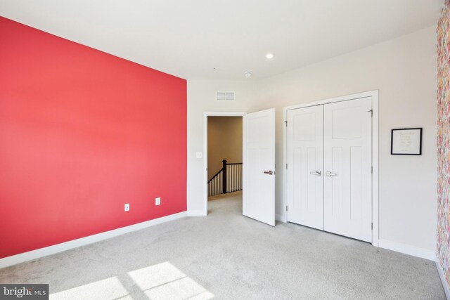 unfurnished bedroom with a closet, visible vents, baseboards, and carpet floors