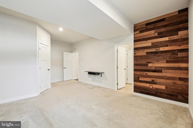 unfurnished living room with wooden walls, recessed lighting, baseboards, and carpet floors