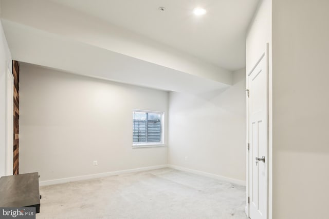 spare room featuring baseboards and light carpet