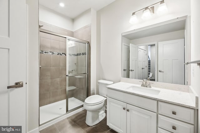 bathroom with tile patterned floors, toilet, a stall shower, and vanity