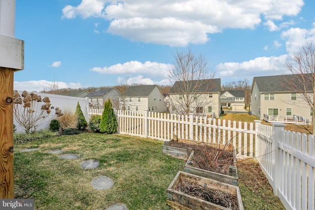 view of yard featuring a fenced backyard, a residential view, and a vegetable garden