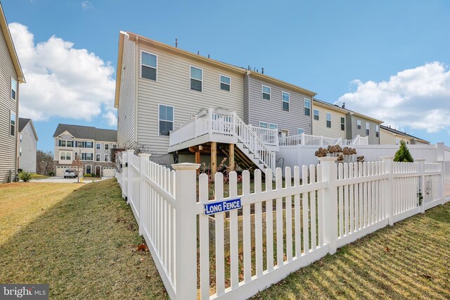 back of house with a deck, a fenced backyard, a lawn, and a residential view