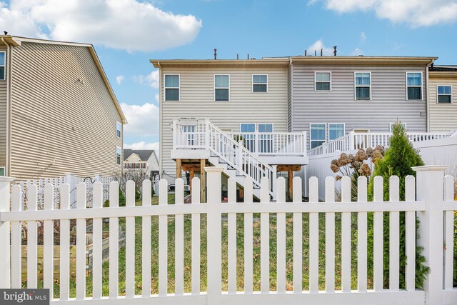 back of property with a fenced front yard, a deck, and stairs