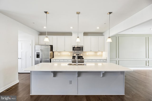 kitchen featuring visible vents, decorative backsplash, stainless steel appliances, white cabinetry, and a sink