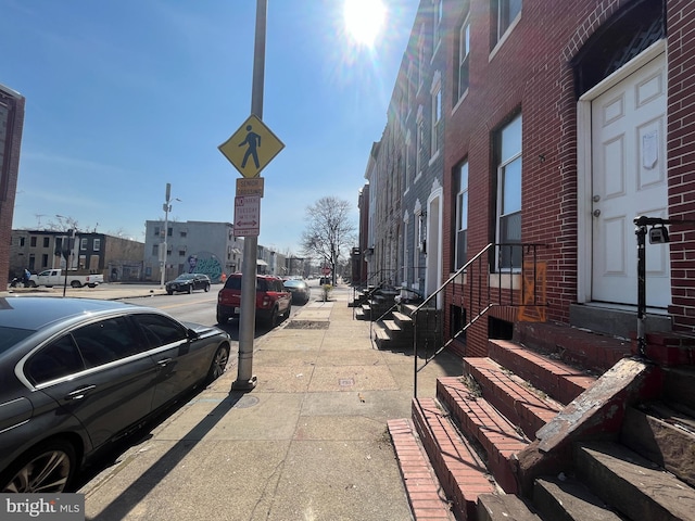 view of road featuring curbs, entry steps, traffic signs, and sidewalks