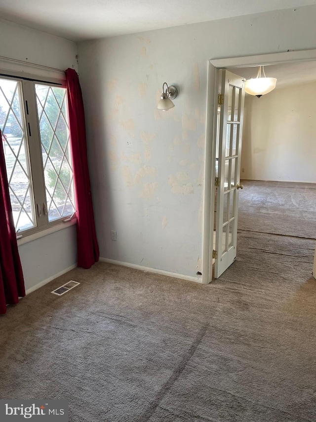 carpeted spare room with a wealth of natural light, visible vents, and baseboards