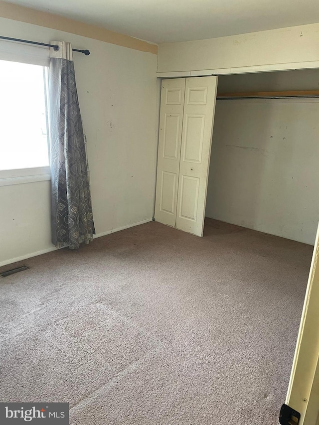 unfurnished bedroom featuring carpet flooring, visible vents, and a closet