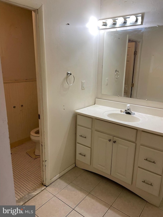 bathroom with vanity, tile patterned floors, toilet, and wainscoting