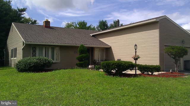 view of front of home with a garage, a chimney, a front lawn, and a shingled roof