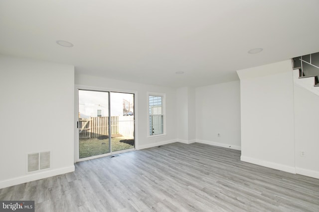 spare room featuring visible vents, baseboards, wood finished floors, and stairs