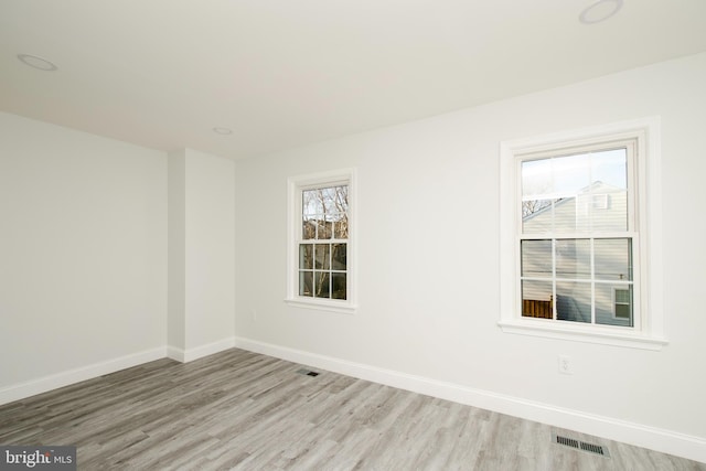 unfurnished room featuring visible vents, baseboards, and wood finished floors