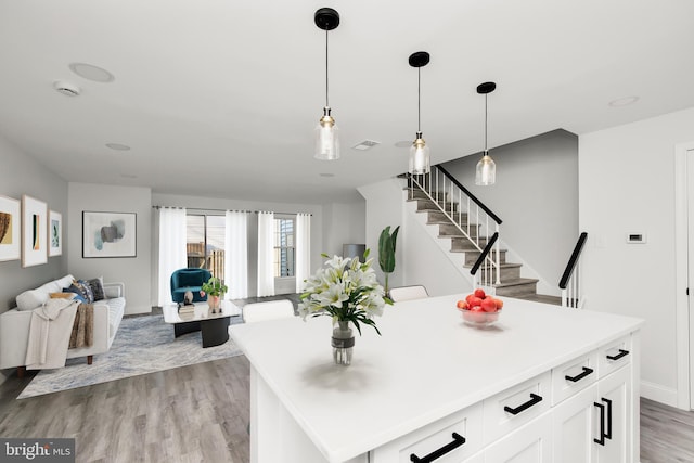 kitchen with light wood-style flooring, a kitchen island, open floor plan, white cabinetry, and light countertops